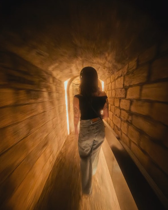 A visitor walking into a warm-lit quarry tunnel beneath Paris