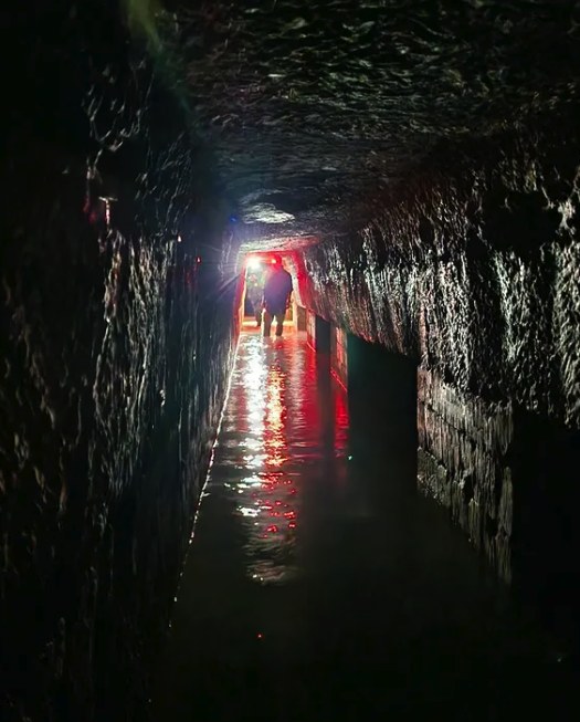 Water reflecting a red light in a dark quarry tunnel below Paris